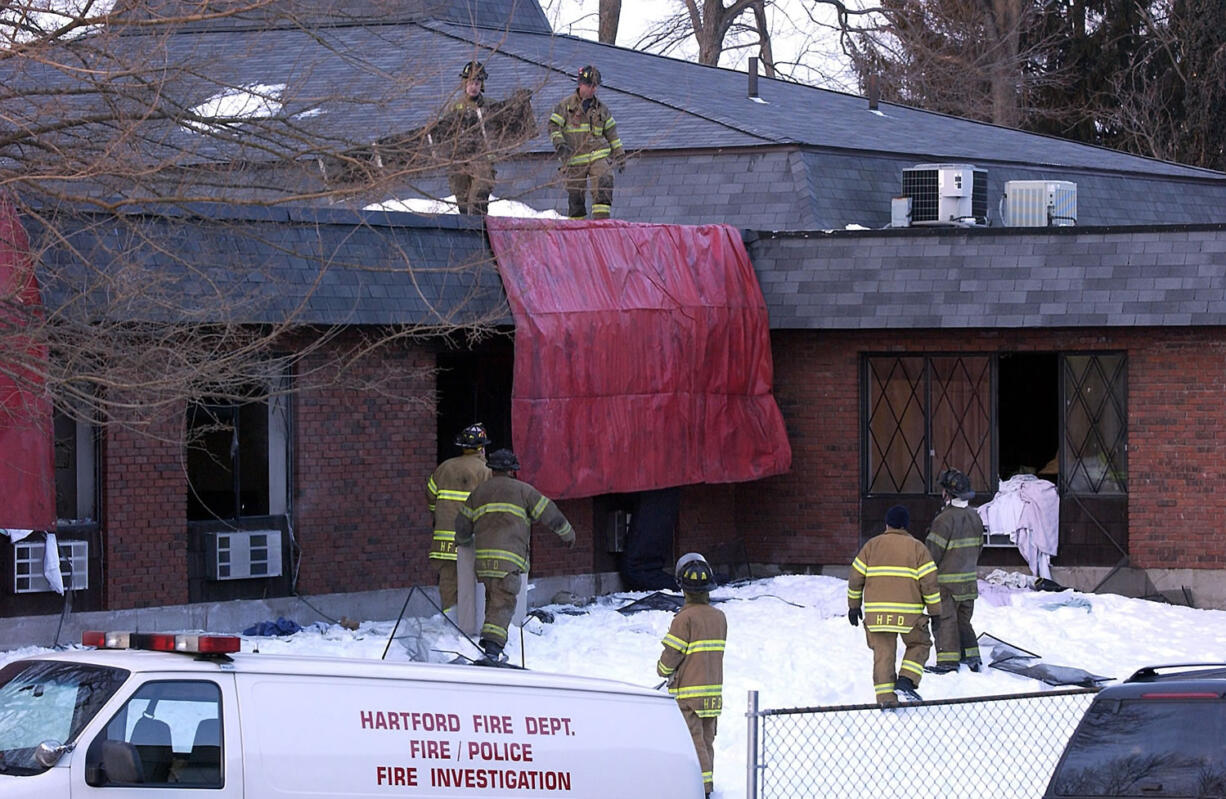 Firefighters work on the roof of the Greenwood Health Center in Hartford, Conn., on Feb. 26, 2003.