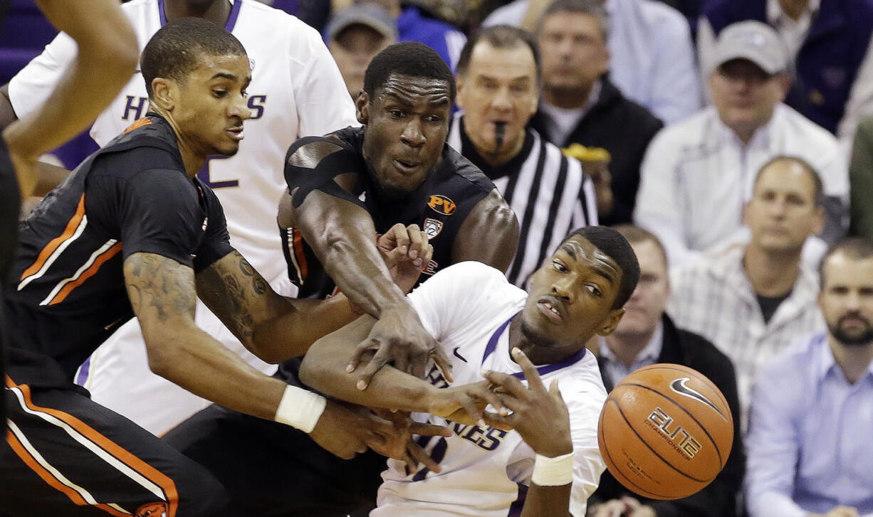 Washington's Mike Anderson, front right, and Oregon State's Gary Payton II, left, and Daniel Gomis reach for a loose ball in the first half Thursday, Jan. 15, 2015, in Seattle.