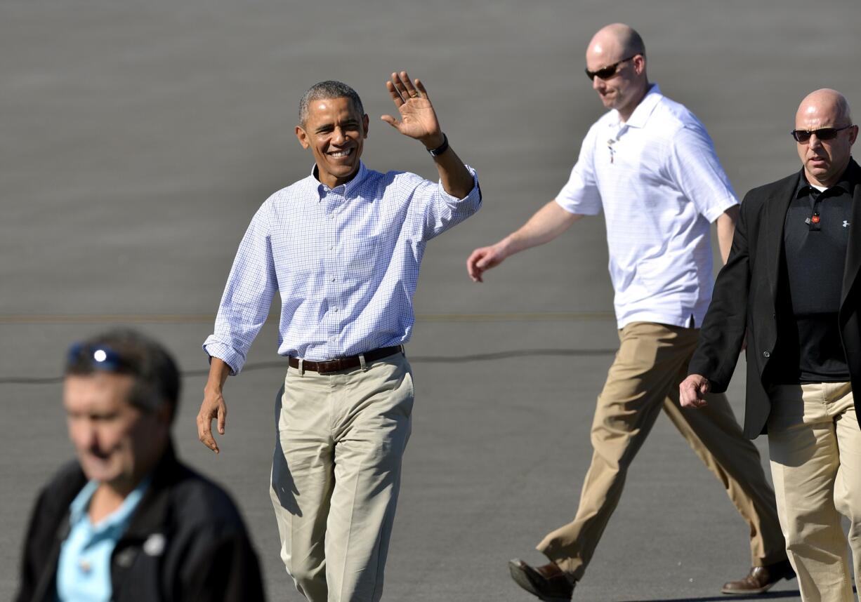 President Barack Obama waves to the media while walking to meet with greeters after arriving aboard Air Force One at Palm Springs International airport, on Saturday in Palm Springs, Calif.