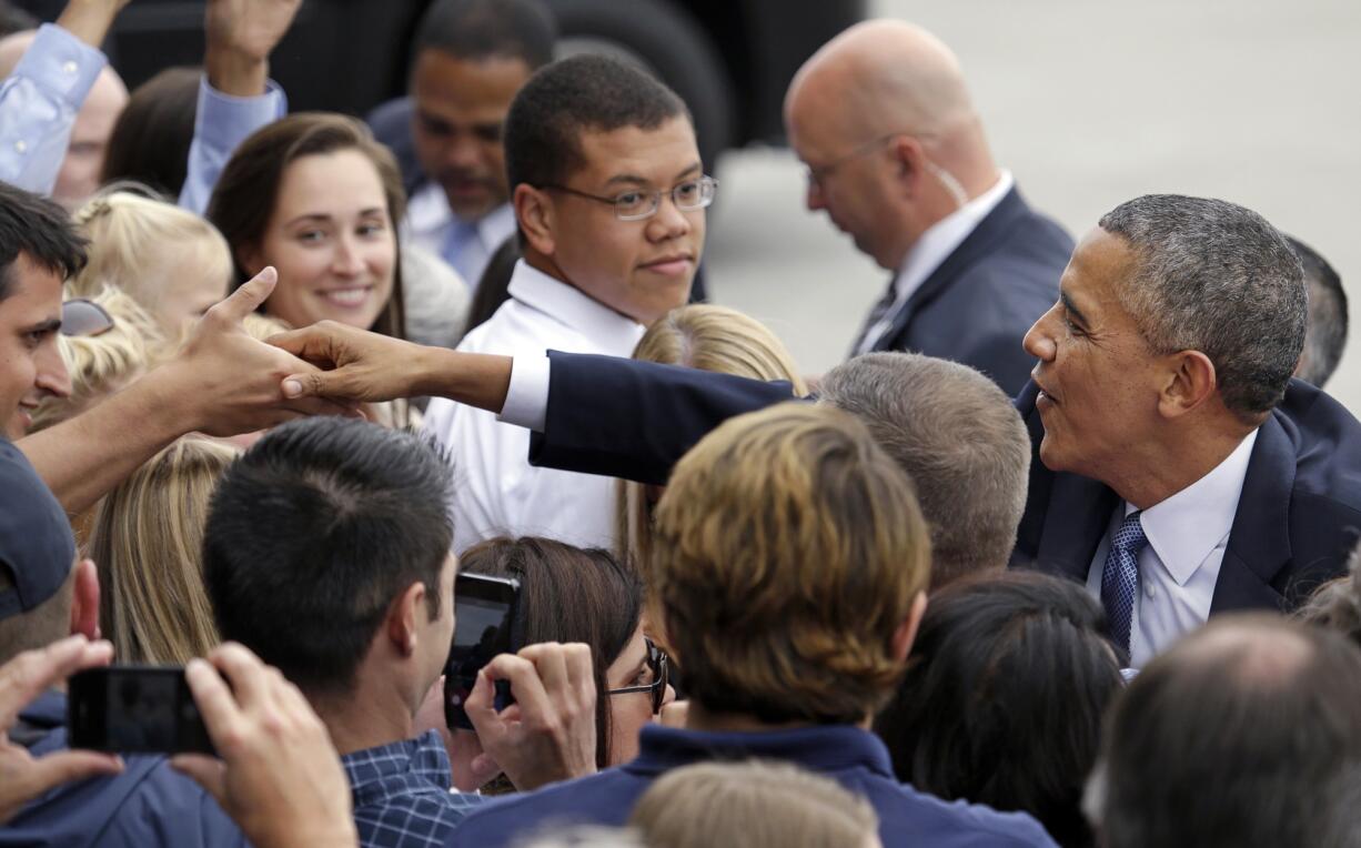 President Barack Obama reaches deep into a crowd to greet people on his arrival Tuesday in Seattle.