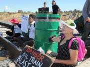 Oil train protestors, from left, Annette Klapstein of Bainbridge Island, Adam Gaya of Seattle and Jan Woodruff of Anacortes sit on the tracks at the Texas Road crossing on March's Point to block a train from leaving the Tesoro Refinery railroad yard in Anacortes on July 28.