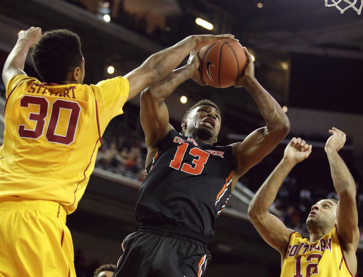 Oregon State's Langston Morris-Walker, center, gets his shot blocked by Southern California's Elijah Stewart, left, during the second half Saturday, Feb. 14, 2015, in Los Angeles. USC won 68-55. (AP Photo/Jae C.