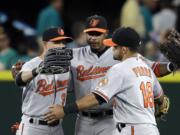 Baltimore Orioles outfielders David Lough (9), Adam Jones and Gerardo Parra (18) hug after the team beat the Seattle Mariners 3-2 on Monday, Aug. 10, 2015, in Seattle.