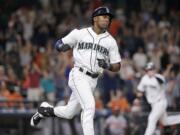 Seattle Mariners' Austin Jackson heads to first after knocking in the winning run as Logan Morrison heads home to score against the Baltimore Orioles in the 10th inning Tuesday, Aug. 11, 2015, in Seattle.