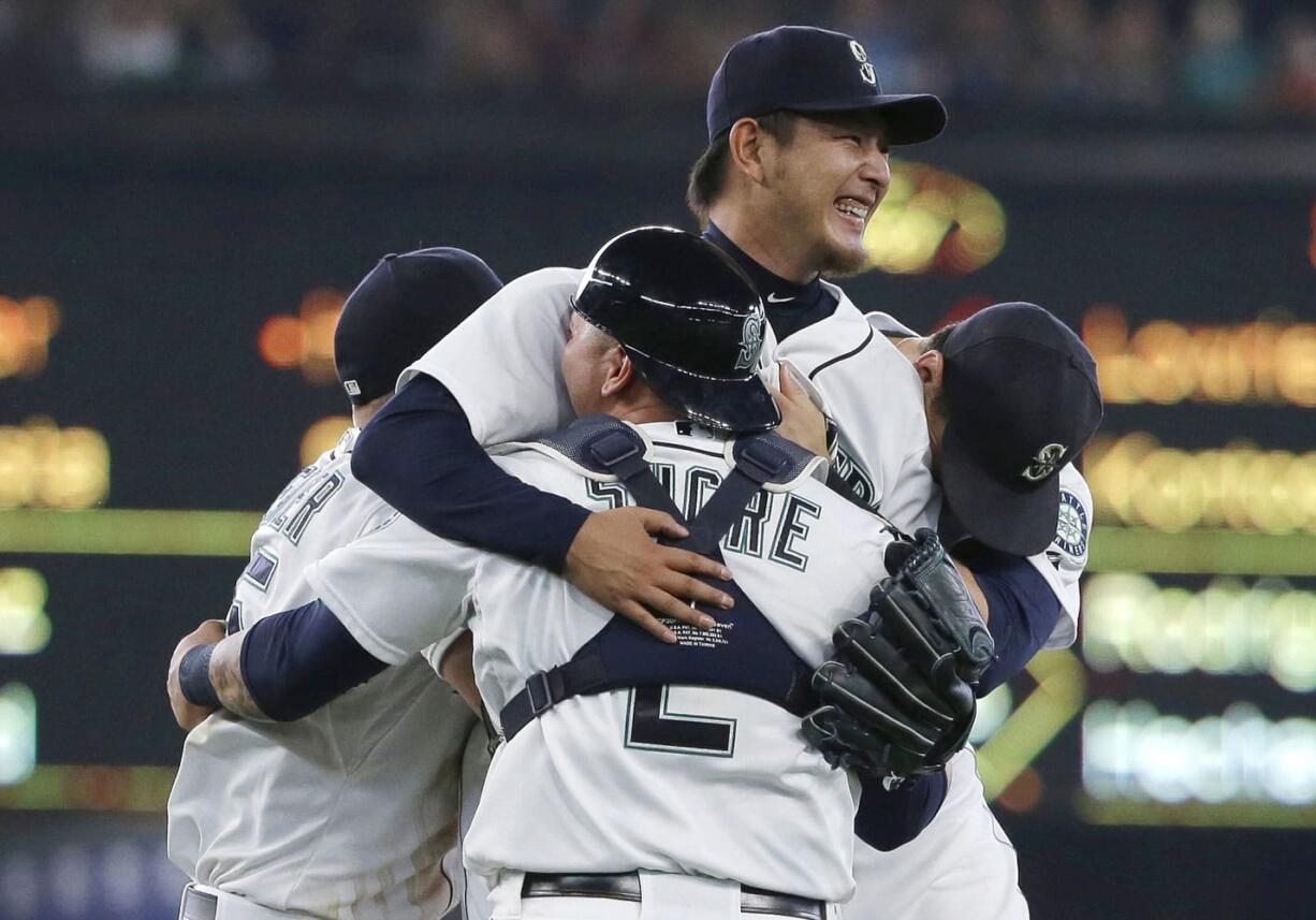 Seattle Mariners starting pitcher Hisashi Iwakuma, center, is mobbed by teammates, including catcher Jesus Sucre (2), after Iwakuma threw a no-hitter against the Baltimore Orioles in a baseball game Wednesday, Aug. 12, 2015, in Seattle. The Mariners won 3-0. (AP Photo/Ted S.