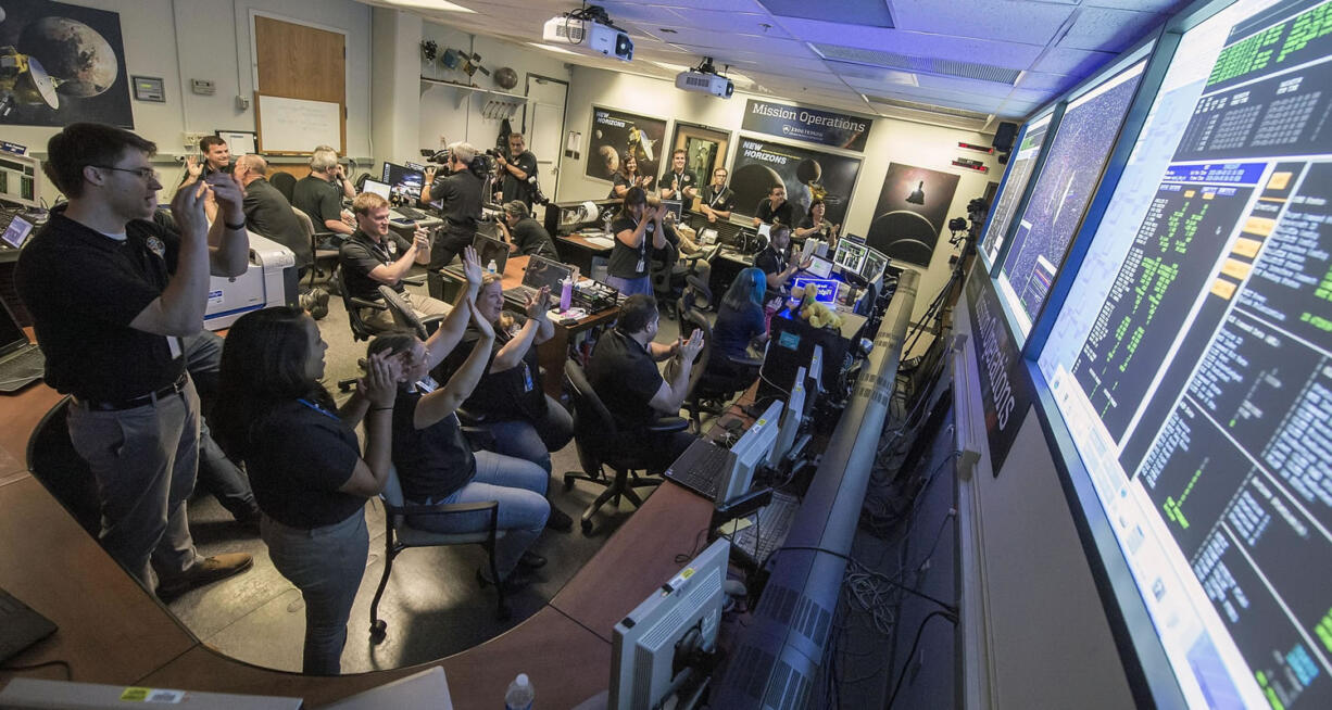 New Horizons flight controllers celebrate after they received confirmation from the spacecraft that it had successfully completed the flyby of Pluto on Tuesday at the Johns Hopkins University Applied Physics Laboratory in Laurel, Md.