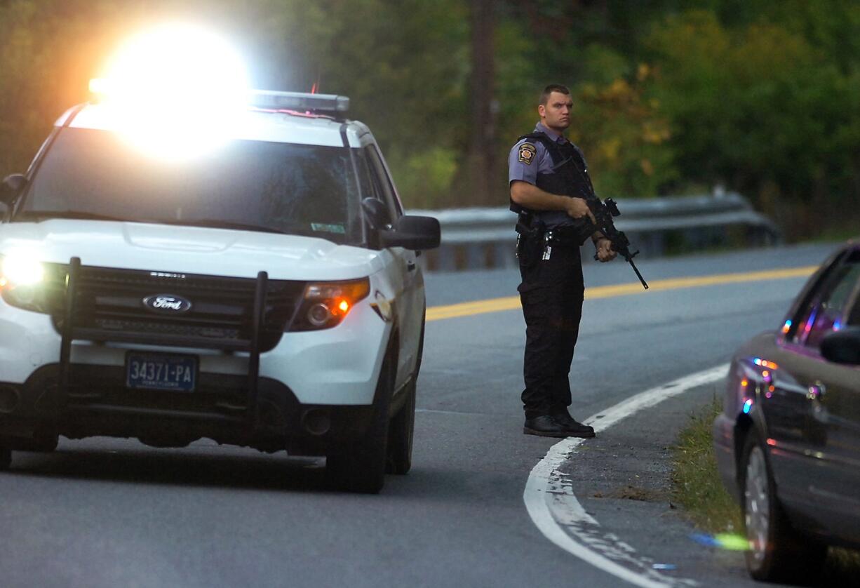 A Pennsylvania State Trooper stands with his weapon ready on Route 447 in Price Township on Sunday near Canadensis, Pa., during a massive search for suspected killer Eric Frein.