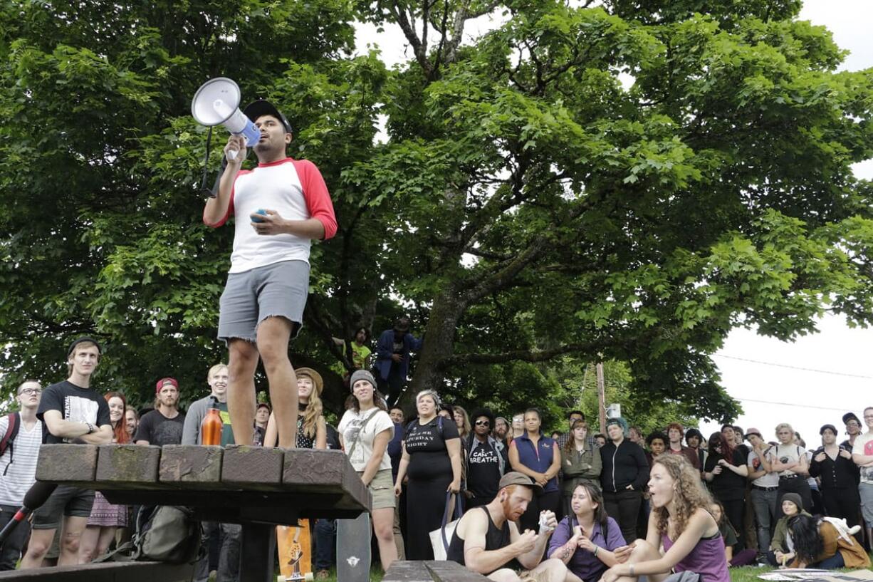 Rafael Ruiz speaks through a megaphone to a crowd gathered at a park to protest a police shooting in Olympia on Thursday.