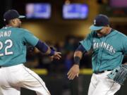 Seattle Mariners Robinson Cano (22) and Nelson Cruz share congratulations after the Mariners defeated the Texas Rangers 4-3 in a baseball game Friday, Aug. 7, 2015, in Seattle.