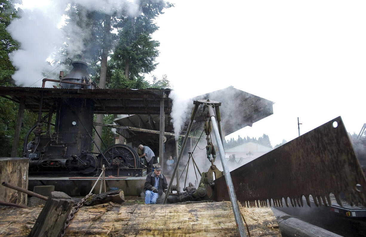 Volunteer Ralph Parker, 73, center, runs a steam drag saw that once operated at a mill in Carson, during the Rural Heritage Fair.