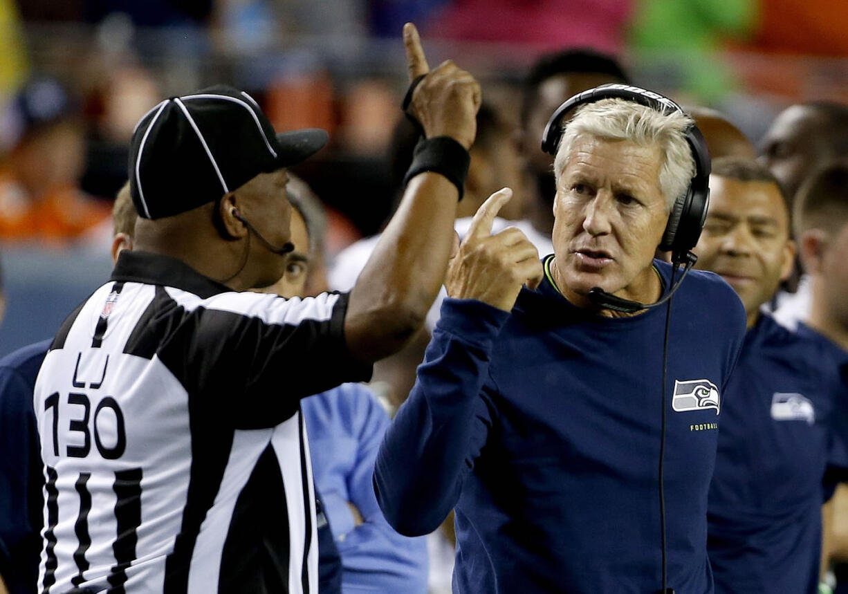 Seattle Seahawks coach Pete Carroll talks to line judge Darryll Lewis (130) during the second half of an NFL preseason game against the Denver Broncos, Thursday, Aug. 7, 2014, in Denver.