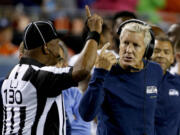 Seattle Seahawks coach Pete Carroll talks to line judge Darryll Lewis (130) during the second half of an NFL preseason game against the Denver Broncos, Thursday, Aug. 7, 2014, in Denver.