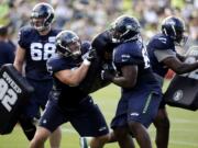 Seattle Seahawks Kristjan Sokoli, second left, and Patrick Lewis push against each other in a drill at a training camp.