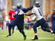 Seattle Times photo
Seattle Seahawks running back Marshawn Lynch, left, lays a stiff arm on linebacker Marcus Dowtin during training camp Tuesday  in Renton. After talking to the running back, the Seahawks said the assault allegations against Lynch are without merit.