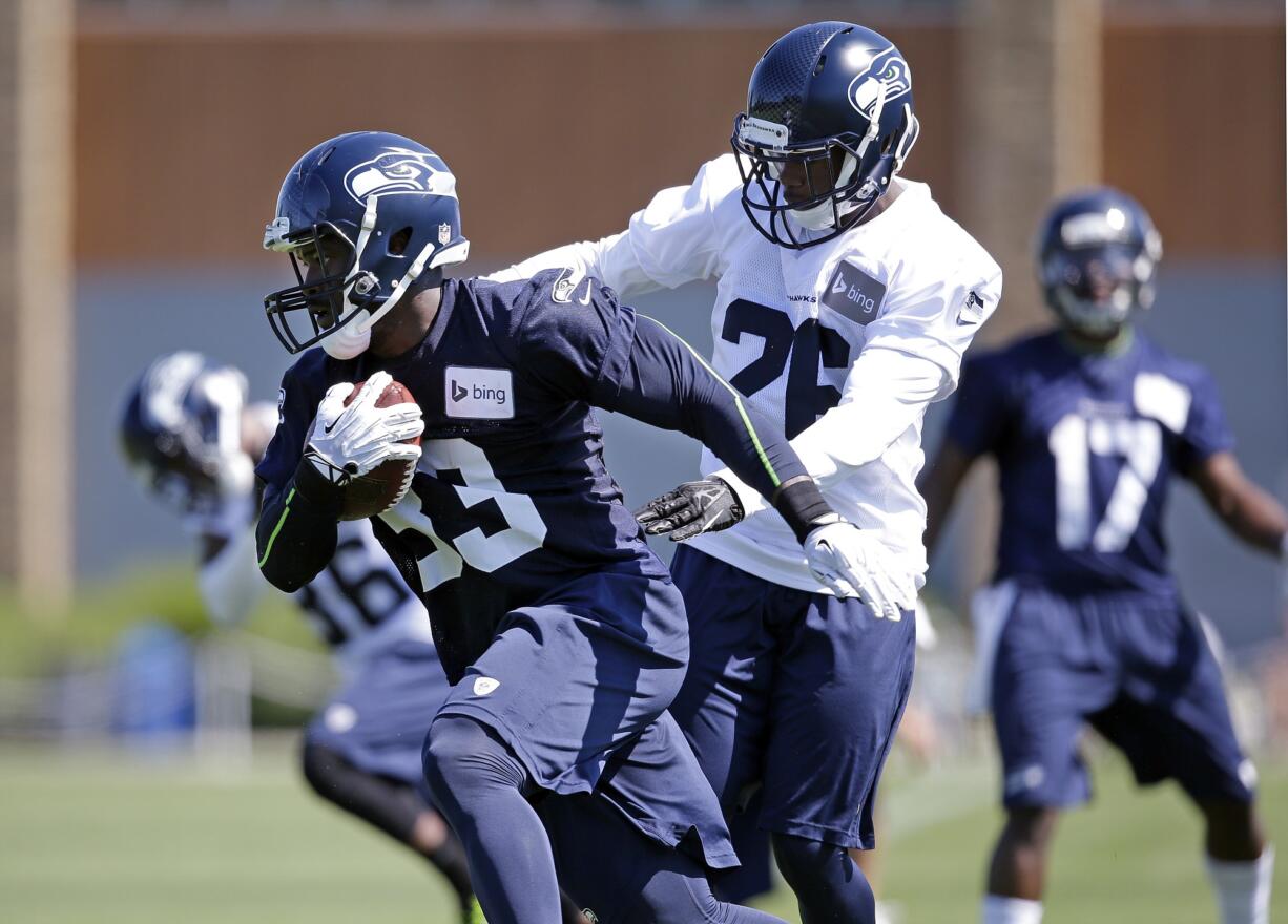 Seattle Seahawks' Christine Michael (33) runs past Michael Robinson at an NFL football camp practice on Saturday, July 26, 2014, in Renton.