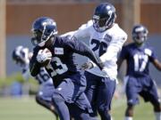 Seattle Seahawks' Christine Michael (33) runs past Michael Robinson at an NFL football camp practice on Saturday, July 26, 2014, in Renton.