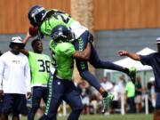 Seattle Seahawks cornerback DeShawn Shead (35) picks up fellow cornerback Richard Sherman (25) during the team's scrimmage, Saturday, Aug. 8, 2015, in Renton.