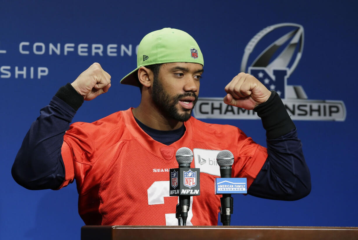 Seattle Seahawks quarterback Russell Wilson raises his arms and ends his remarks to reporters with his traditional &quot;Go Hawks!,&quot; Wednesday before practice in Renton. The Seahawks will face the Green Bay Packers, Sunday in the NFC Championship game. (AP Photo/Ted S.