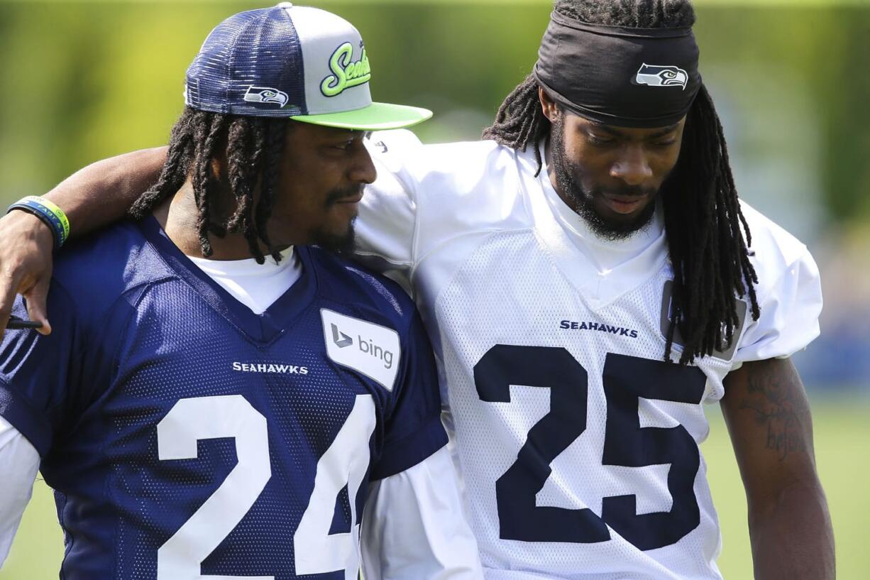 Seattle Seahawks running back Marshawn Lynch, left, walks off the field with cornerback Richard Sherman, right, after Friday's training camp session in Renton. It was Lynch's first day attending training camp after staying away due to contract issues. (AP Photo/Ted S.