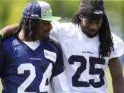 Seattle Seahawks running back Marshawn Lynch, left, walks off the field with cornerback Richard Sherman, right, after Friday's training camp session in Renton. It was Lynch's first day attending training camp after staying away due to contract issues. (AP Photo/Ted S.