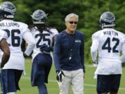 Seattle Seahawks head coach Pete Carroll walks by defensive players during Tuesday's organized team activity in Renton.