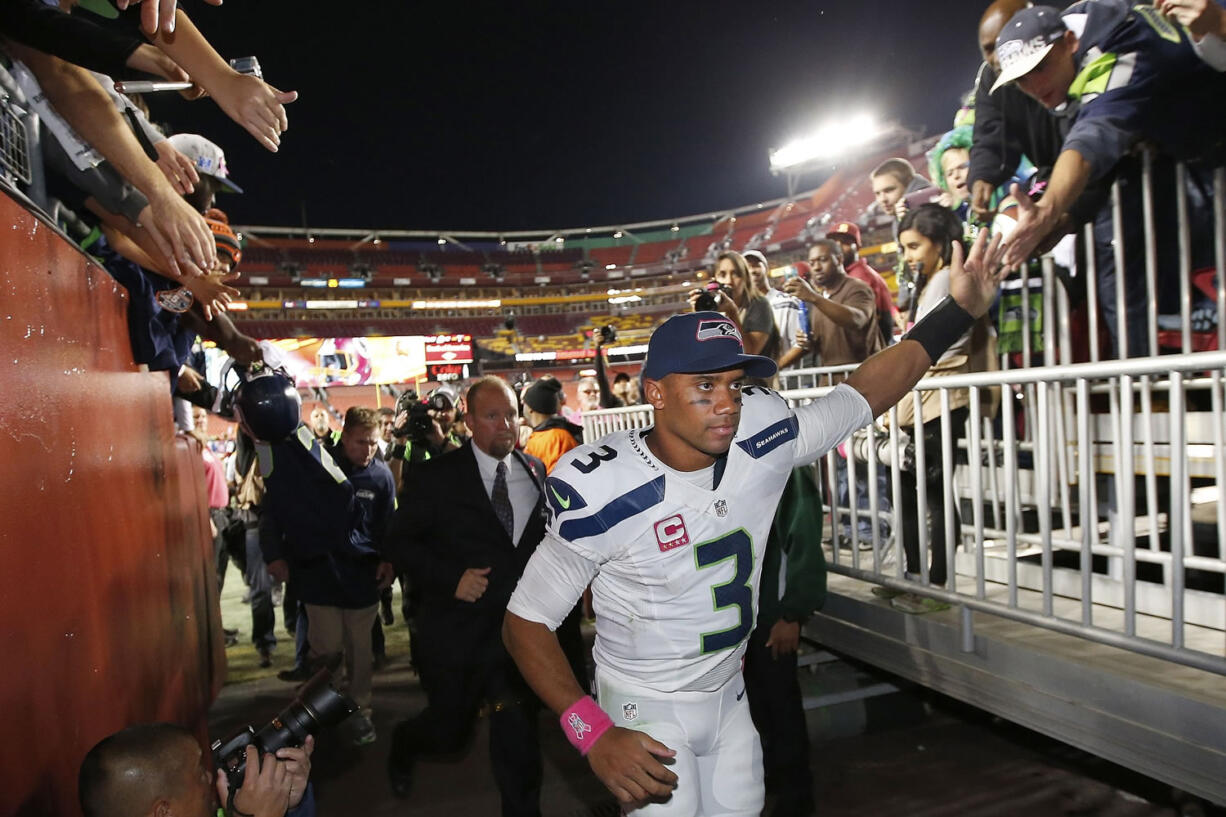 Seattle Seahawks quarterback Russell Wilson (3) reaches for the fans as he leaves the field  an NFL football game against the Washington Redskins in Landover, Md., Monday, Oct. 6, 2014. Seattle defeated Washington 27-17.