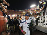 Seattle Seahawks quarterback Russell Wilson (3) reaches for the fans as he leaves the field  an NFL football game against the Washington Redskins in Landover, Md., Monday, Oct. 6, 2014. Seattle defeated Washington 27-17.