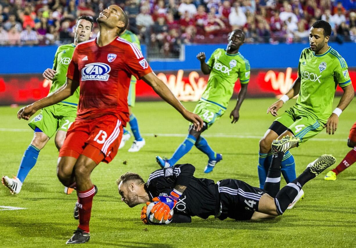 FC Dallas forward Tesho Akindele (13) reacts to Seattle Sounders FC goalkeeper Stefan Frei (24) stealing the ball during the first half of a MLS soccer game Saturday, March 28, 2015, in Frisco, Texas.