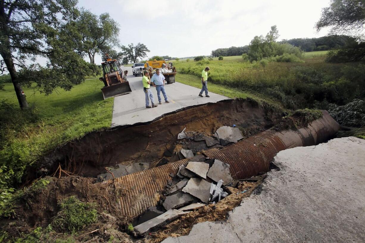 Kane County crews look over a sinkhole in Burlington Township, Ill., on Tuesday where three people escaped serious injury when two vehicles traveled into the sinkhole on a rural stretch of road.