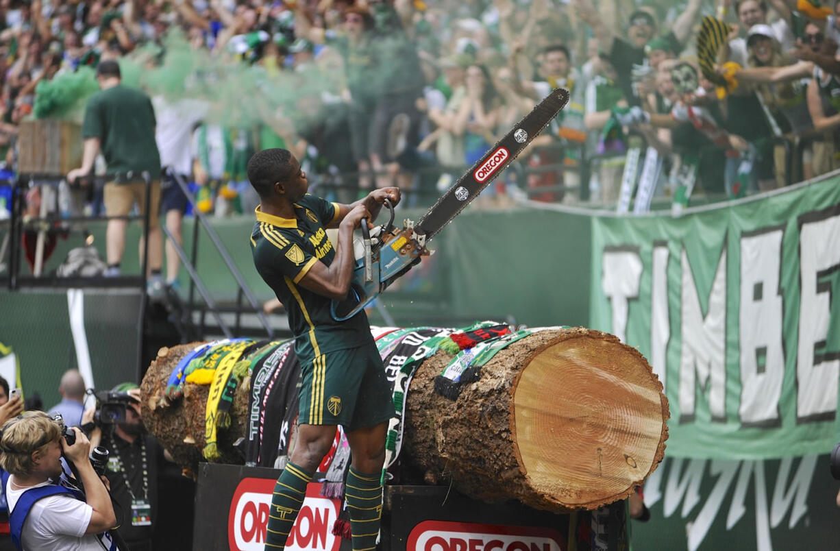 Portland Timbers' Fanendo Adi (9) celebrates his goal by jumping the fence and holding up Timber Joey's chainsaw for the fans during the second half Sunday in Portland. Portland beat Seattle 4-1.