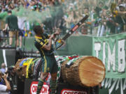 Portland Timbers' Fanendo Adi (9) celebrates his goal by jumping the fence and holding up Timber Joey's chainsaw for the fans during the second half Sunday in Portland. Portland beat Seattle 4-1.