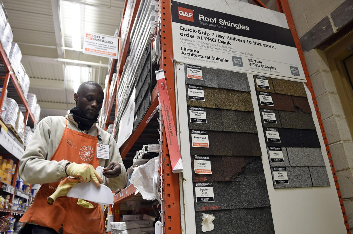 Prince Addy of Manassas, Va., straightens up the shelves of roofing products at the Home Depot in Falls Church, Va. Winter takes a toll on roofs.