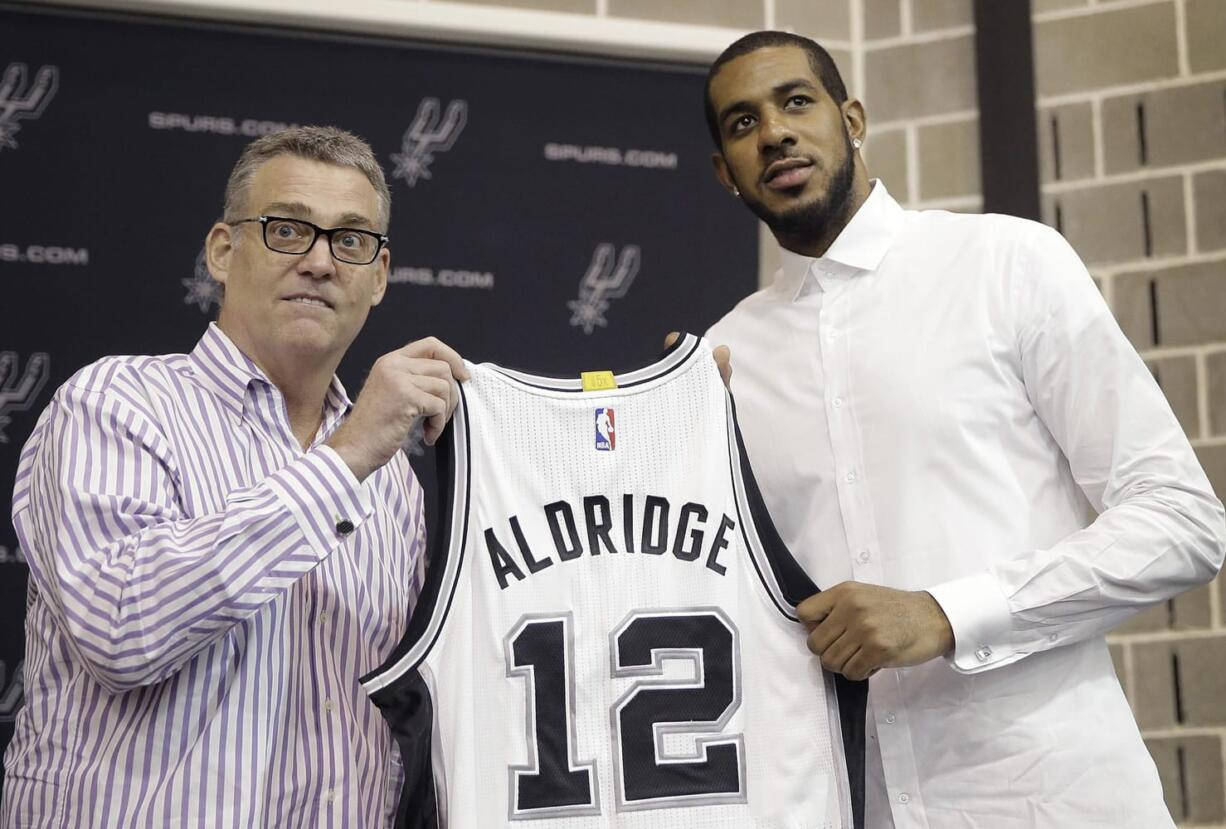 LaMarcus Aldridge, right, poses with San Antonio Spurs general manager R.C. Buford, left, and his new jersey during a news conference at the team's practice facility as he is formally introduced after he signed with the San Antonio Spurs, Friday, July 10, 2015, in San Antonio.