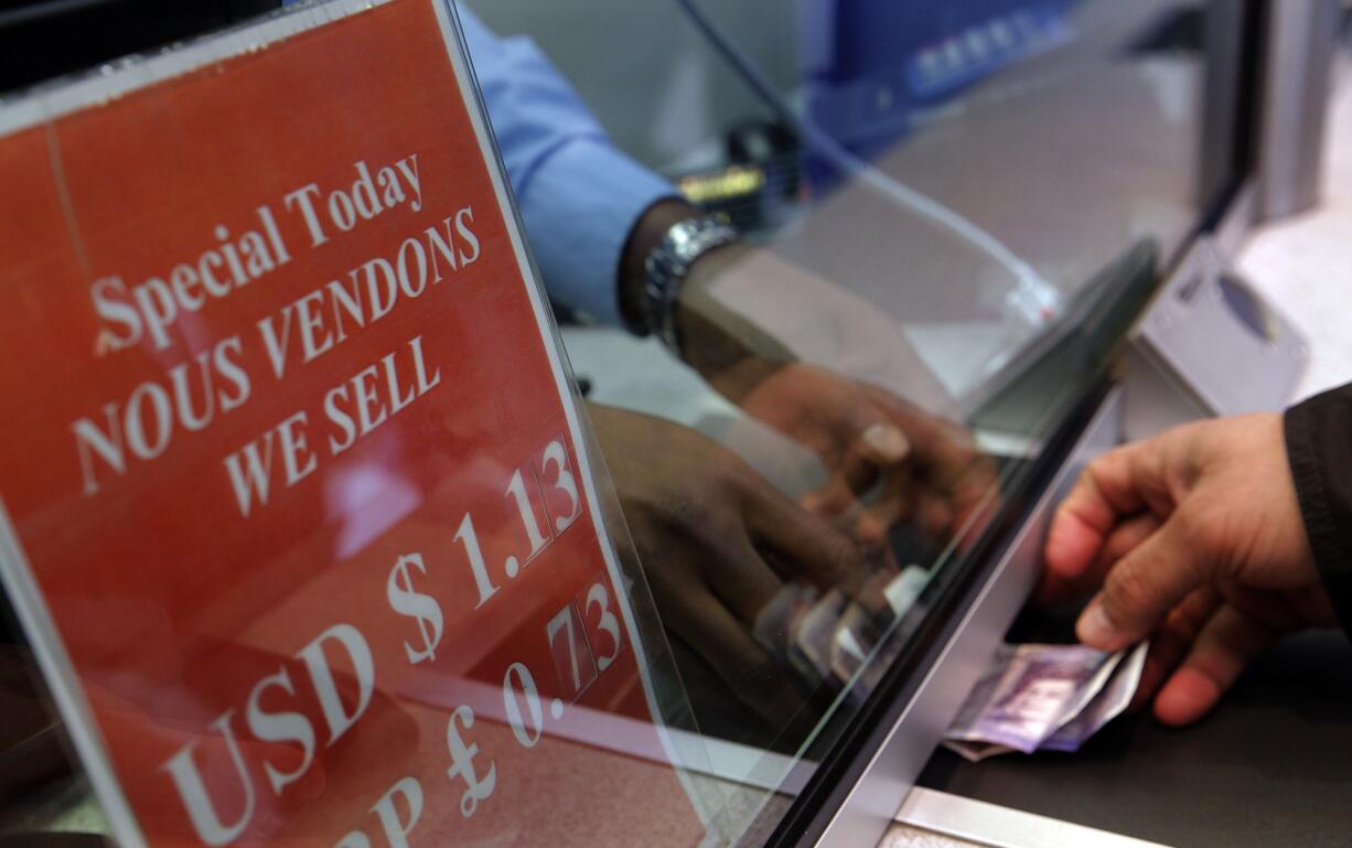 A man exchanges money Jan. 6 at a currency exchange office on the Champs Elysees in Paris. Long a symbol of American economic might, the rising dollar is denting the earnings of U.S.