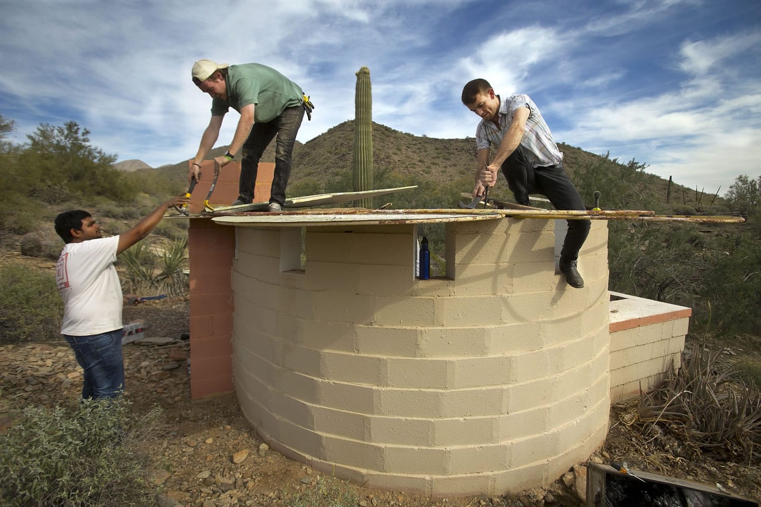 Students in the Frank Lloyd Wright School of Architecture, from left; Soham Shah, Garth Lindquist and Connor Bingham work Saturday, Feb. 22, 2014, on restoring the &quot;Lotus Shelter&quot; that was built in 1963 by Valley architect Kamal Amin, at Taliesin West in Scottsdale, Ariz.   The Lotus Shelter  is half-enclosed in a curved line of concrete block wall oriented toward the morning sun. The metal roof is a floating lotus-like design, and painted sunny yellow in the interior with a fireplace and chimney in the rear.