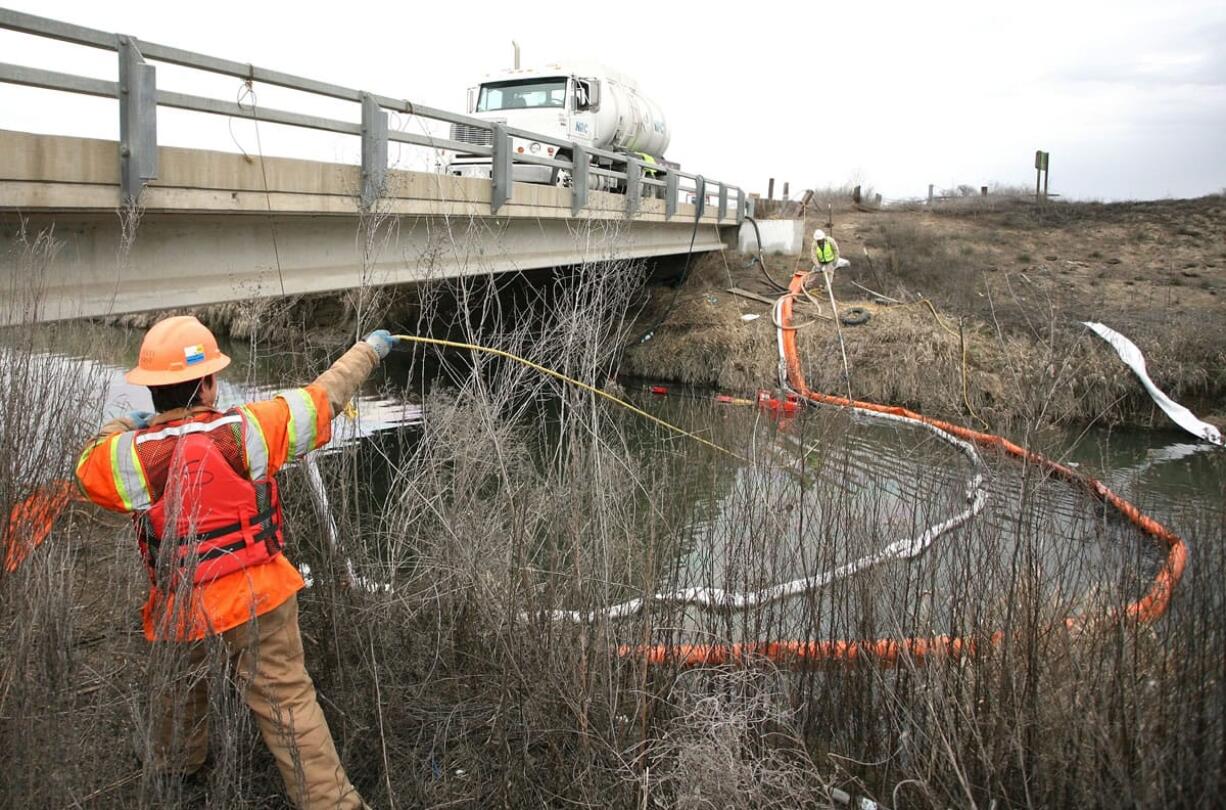 Stuart Weisenberger, a boom tender with environmental cleanup firm NRC, moves a vacuum tube upstream  in Sulphur Creek south of Sunnyside.