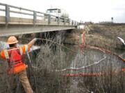 Stuart Weisenberger, a boom tender with environmental cleanup firm NRC, moves a vacuum tube upstream  in Sulphur Creek south of Sunnyside.