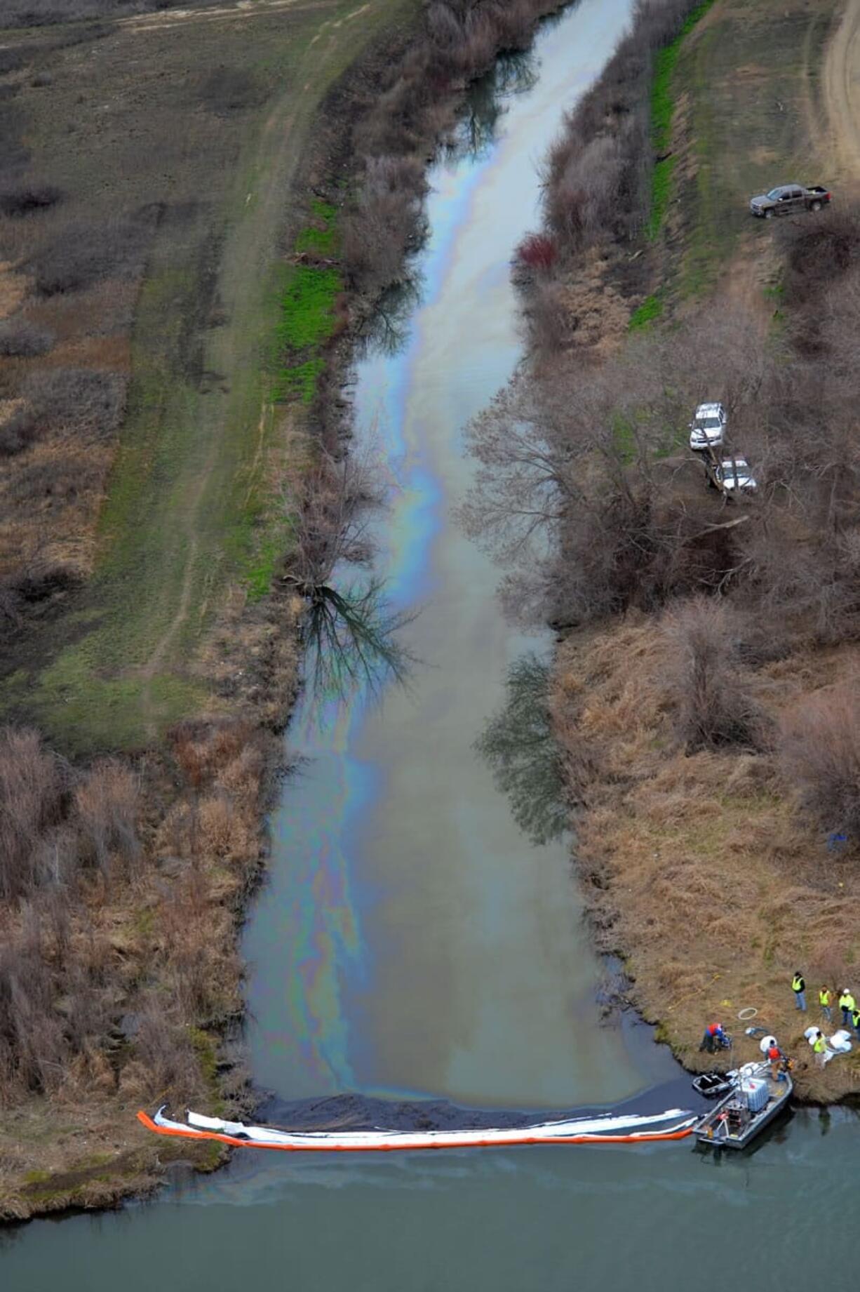 In this aerial photo taken Monday, March 2, 2015, and provided by the Washington Dept. of Ecology, boom tenders try to contain an oil spill on Sulphur Creek where it enters the Yakima River near Sunnyside, Wash. The Washington state Ecology Department said Tuesday, March 3, 2015, that about 50 birds have been covered in oil from the spill that leaked as much as 1,500 gallons of used motor oil into irrigation canals and the Yakima River. (AP Photo/Washington Dept.