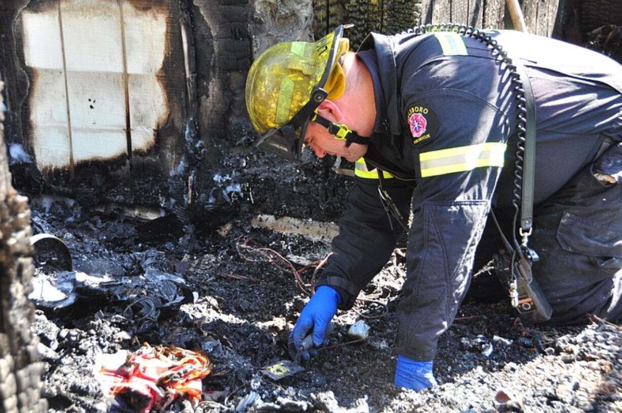 A fire investigator looks through the ruins of a Hillsboro, Ore.