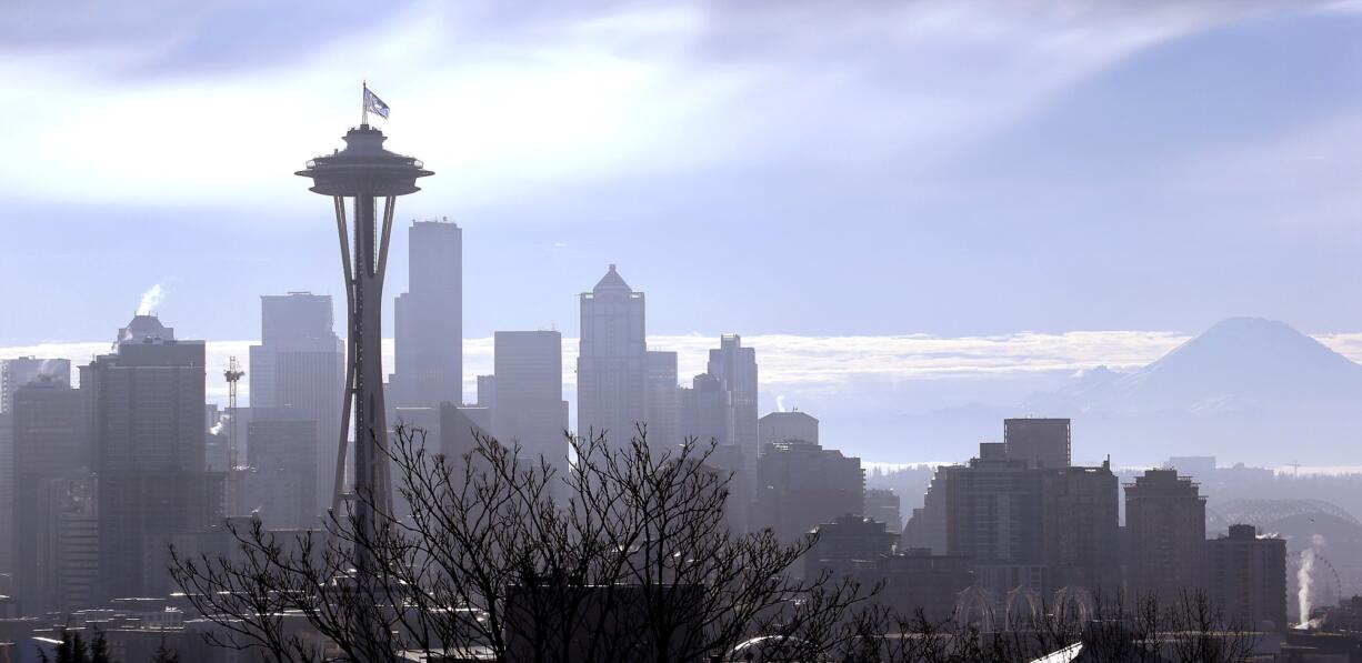 With Mount Rainier, right, visible in the distance, a &quot;12th Man&quot; flag, honoring Seattle Seahawks fans, flutters atop the Space Needle after being raised Thursday morning, Jan. 29, 2015, in Seattle. The 25 foot by 35 foot flag will fly atop the 605 foot tall structure through Sunday's Super Bowl XLIX NFL football game between the Seahawks and New England Patriots.