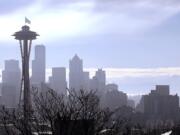 With Mount Rainier, right, visible in the distance, a &quot;12th Man&quot; flag, honoring Seattle Seahawks fans, flutters atop the Space Needle after being raised Thursday morning, Jan. 29, 2015, in Seattle. The 25 foot by 35 foot flag will fly atop the 605 foot tall structure through Sunday's Super Bowl XLIX NFL football game between the Seahawks and New England Patriots.