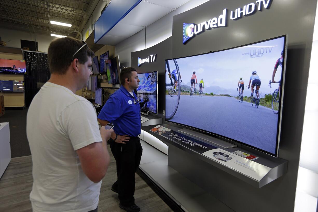 Jake Willis, center, home theatre supervisor at the Best Buy store in Greenwood, Ind., talks with customer Landon Leichter of Spencer, Ind., at a display featuring a Samsung 78-inch curved television.