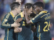 Portland Timbers midfielder Jack Jewsbury, center, is congratulated by defender Jorge Villafana, left, and midfielder George Fochive after Jewsbury scored the winning goal against the Colorado Rapids in Commerce City, Colo.