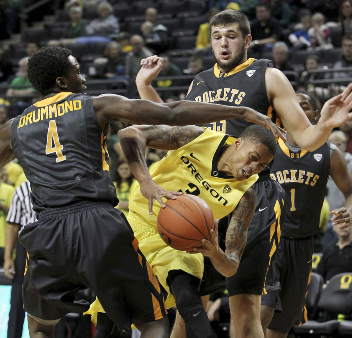 Oregon's Joseph Young, center, looks for a way past Toledo's Justin Drummond, left, and Nathan Boothe, right, during the first half in Eugene, Ore., Friday, Nov. 21, 2014.