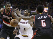 Cleveland Cavaliers' Kyrie Irving, center, drives between Portland Trail Blazers? LaMarcus Aldridge, left, and Will Barton during the fourth quarter of an NBA basketball game Wednesday, Jan. 28, 2015, in Cleveland. Irving scored a team-high 55 points for the Cavaliers 99-94 win.