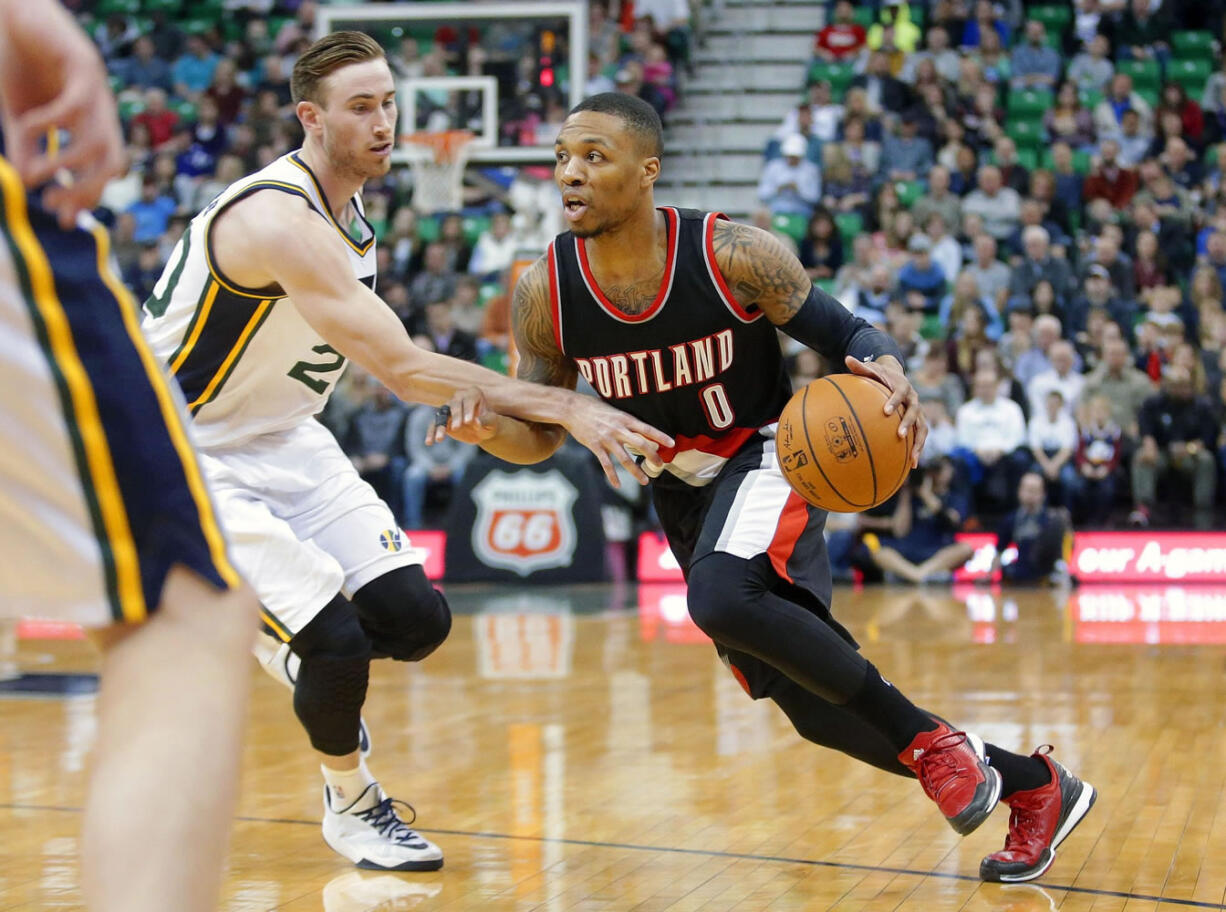 Portland Trail Blazers guard Damian Lillard (0) drives around Utah Jazz forward Gordon Hayward, left, in the second quarter Friday, Feb. 20, 2015, in Salt Lake City.