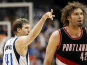 Dallas Mavericks forward Dirk Nowitzki (41), of Germany, points to the seats as Portland Trail Blazers' Robin Lopez (42) walks back to the bench after Nowitzki tied the game with a 3-point basket at the end of regulation Saturday, Feb. 7, 2015, in Dallas. The Mavericks won in overtime 111-101.