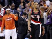 Portland Trail Blazers' Damian Lillard (0) walks away from the Phoenix Suns bench area after he missed a shot, as Suns' Isaiah Thomas, left, pumps his fist in the closing moments of Wednesday's game in Phoenix.