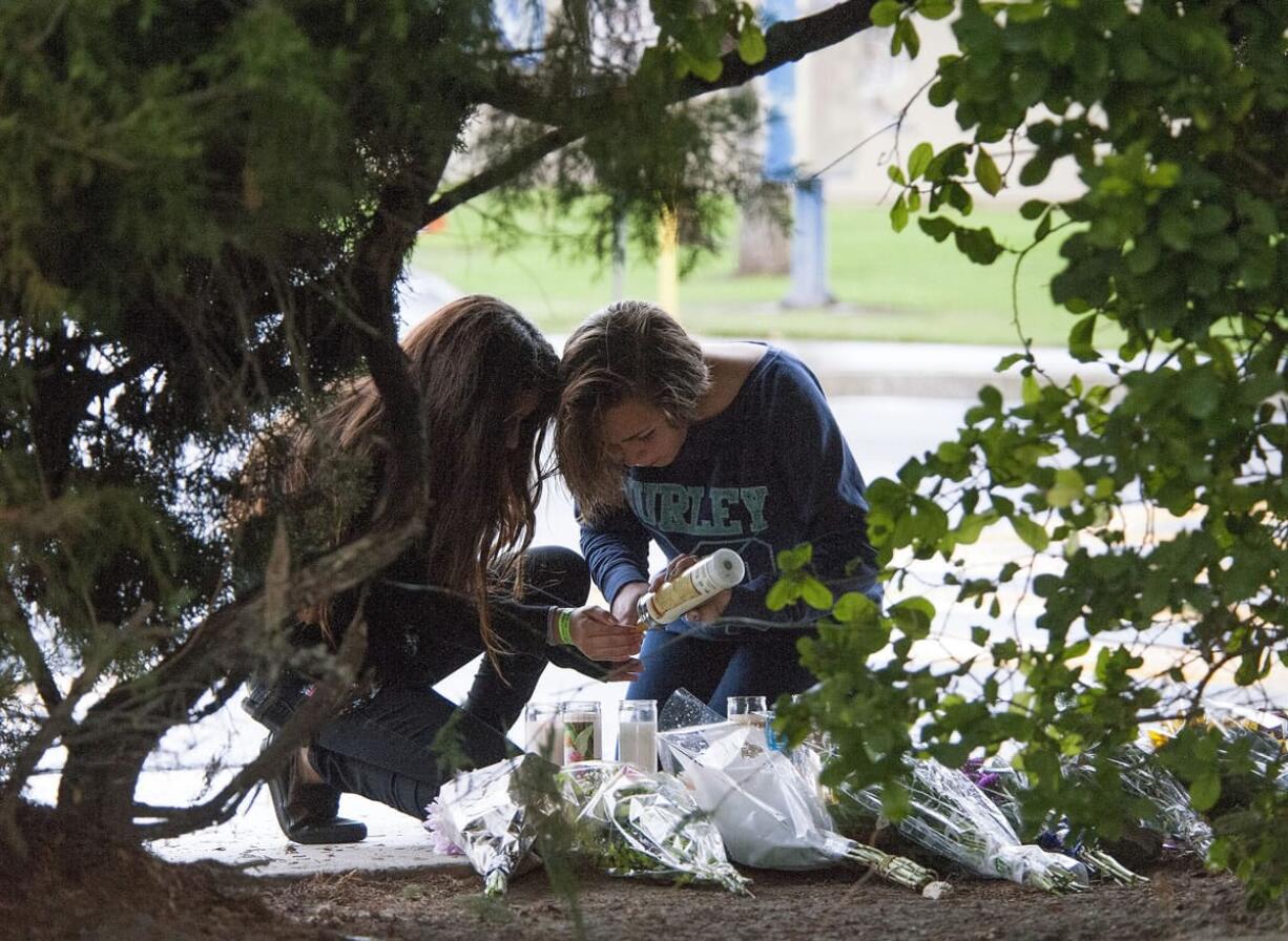 Brianna Diaz, 12, left, and Sandra Anderson, 13, of Orange, Calif. light a candle at a street-side memorial at North Jacaranda Street and Fairhaven Avenue in Santa Ana, Calif. on Saturday, Nov.