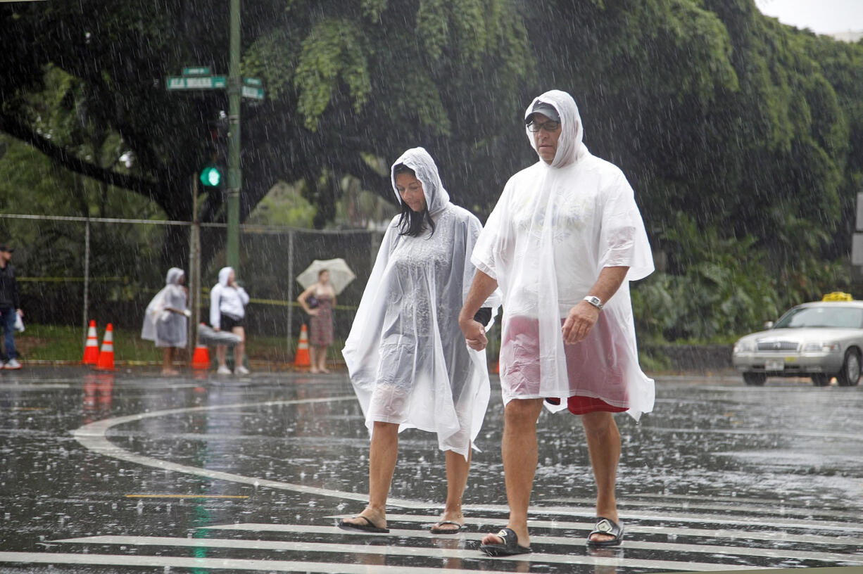 Tourists cope wet weather in Waikiki in Honolulu on Sunday. Hurricane Ana brought a steady rain to the Hawaiian Island of Oahu as it passed about 180 miles west.